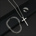 Silver necklace with cross pendant and chain on a dark surface